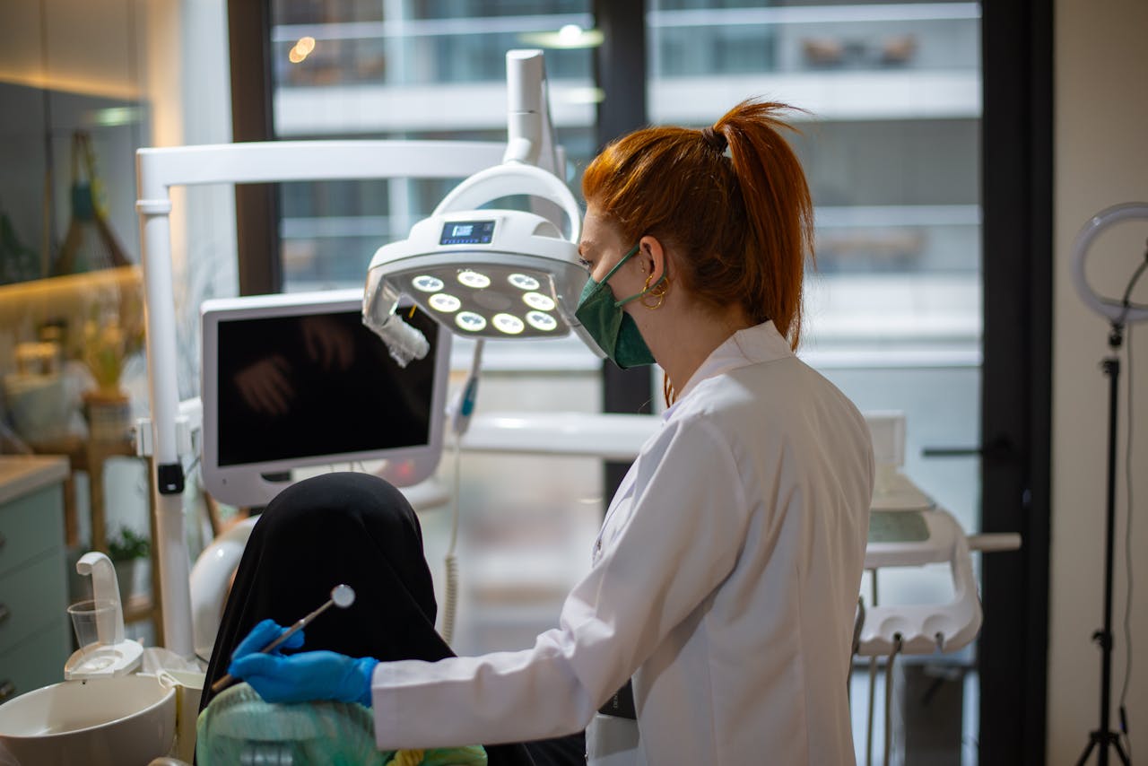 services-03 A dentist wearing a mask attends to a patient in a modern dental clinic with advanced equipment.