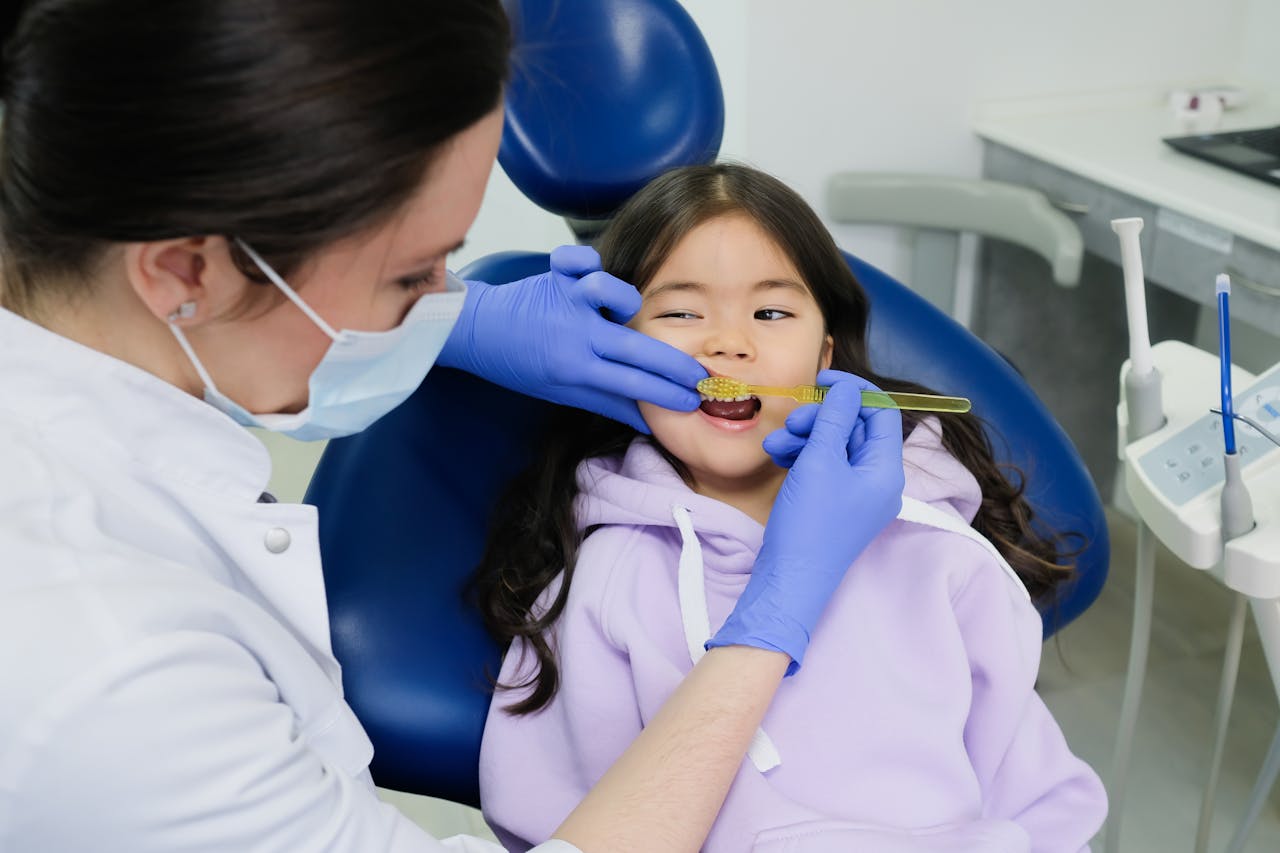 services-02 Female dentist examines a young girl's teeth in a modern dental clinic.
